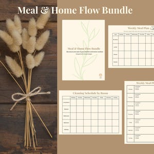 Op de afbeelding: Een bosje gedroogd, pluizig beige konijnenstaartgras, vastgebonden met touw, naast een set beige printbare planners. De planners bevatten een weekmaaltijdplan en een schoonmaakrooster.