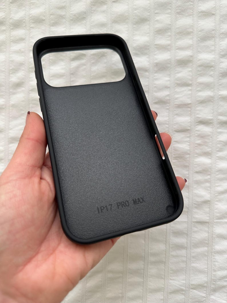 May include: Black phone case with a textured surface. The case has a rectangular camera cutout and the text "IP17 PRO MAX" printed on the inside. The case is designed to protect a phone.