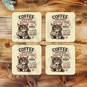 Pode incluir: Quatro porta-copos quadrados com fundo creme apresentando o gráfico de um gatinho rabugento segurando uma caneca de café. O texto diz: COFFEE BECAUSE ADULTING IS HARD... I'D RATHER CAT-NAP INSTEAD. Cada porta-copos é idêntico.