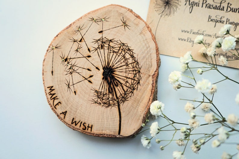 May include: A wooden slice with a burned design of a dandelion with the words "Make a Wish" around the bottom.