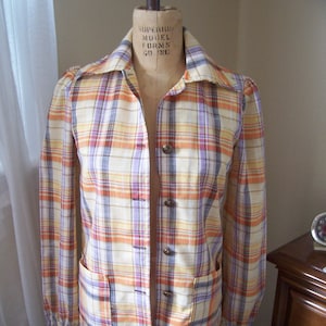 May include: A plaid button-up shirt with long sleeves and a collared neckline. The shirt is in shades of orange, yellow, purple, and white.