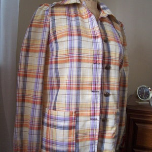 May include: A plaid shirt with long sleeves and a button-up front. The shirt is in shades of orange, yellow, purple, and white.