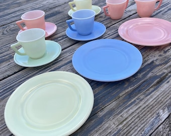 May include: A pastel-colored tea set with six cups and saucers. The cups and saucers are in shades of pink, blue, yellow, and green.