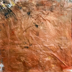 May include: A square sheet of textured, crinkled paper in shades of burnt orange and copper. The surface features irregular creases and folds throughout, with scattered dark brown, black, and faint yellow pigment spots concentrated near the top left corner.