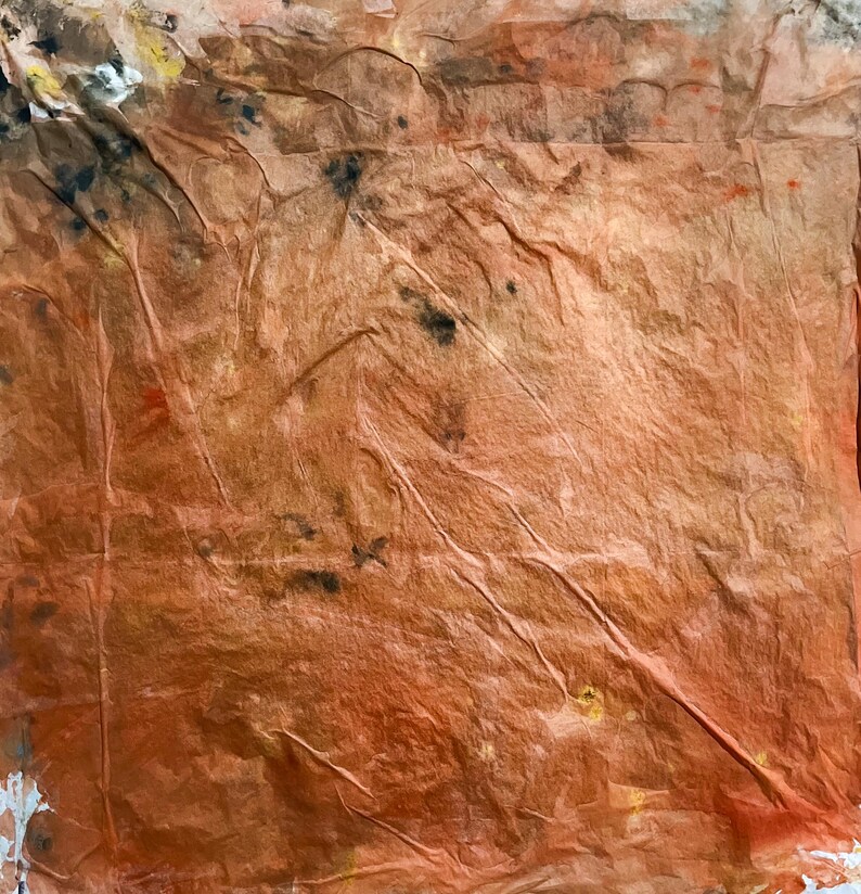 May include: A square sheet of textured, crinkled paper in shades of burnt orange and copper. The surface features irregular creases and folds throughout, with scattered dark brown, black, and faint yellow pigment spots concentrated near the top left corner.