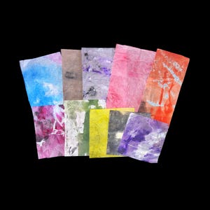 May include: A collection of ten rectangular sheets of textured paper, each featuring a unique abstract pattern in various colors including blue, pink, orange, yellow, purple, green, grey, and brown, arranged in a fan-like overlapping display.