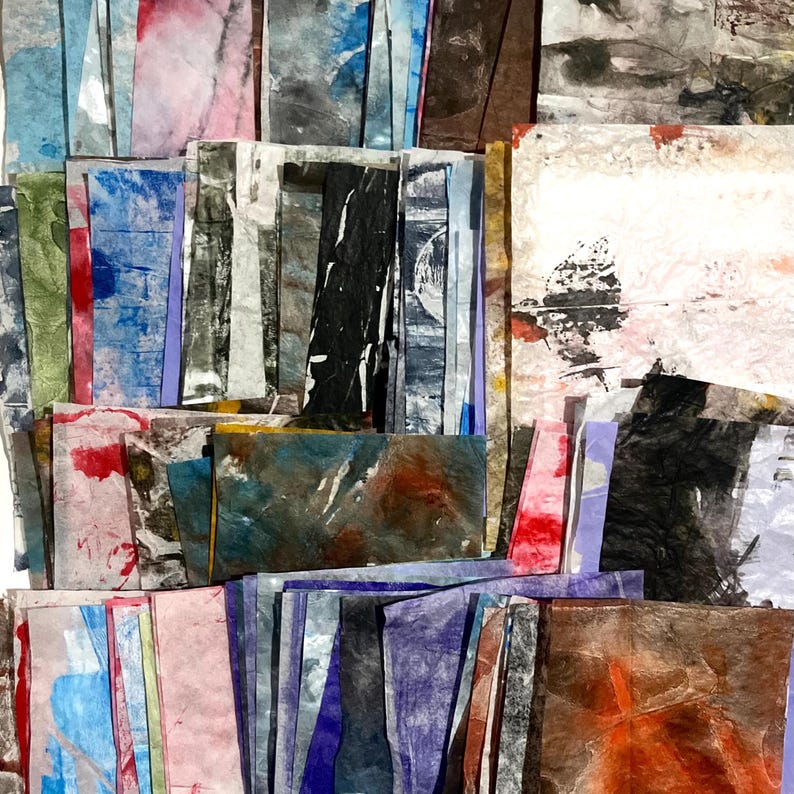 May include: A collection of rectangular paper strips featuring various abstract textures and colors including blue, black, white, red, orange, and brown. The paper pieces are layered and arranged in a dense, overlapping grid-like composition.
