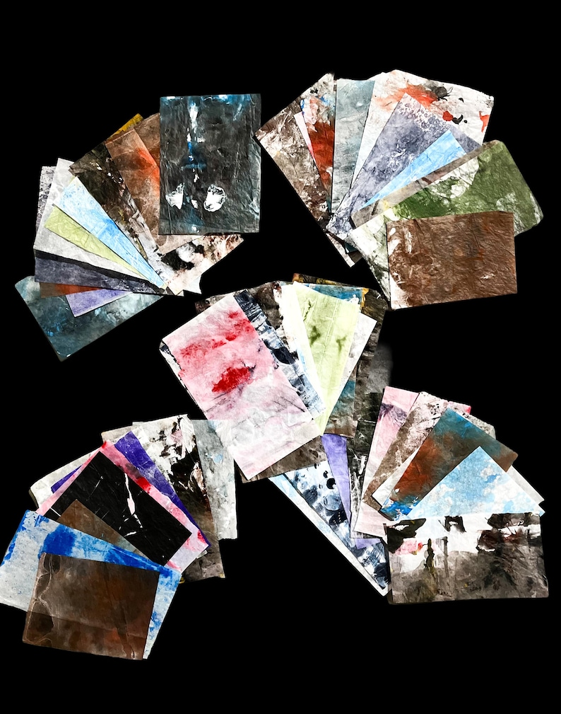 May include: A collection of rectangular paper sheets featuring various abstract paint textures and colors including black, white, blue, red, green, and brown. The papers are arranged in multiple fanned-out stacks, displaying diverse marbled and layered patterns.