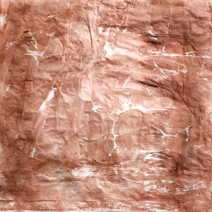 May include: A square piece of textured paper with a wrinkled surface, featuring a monochromatic terracotta brown color palette with subtle white highlights and streaks distributed across the uneven, creased material surface.