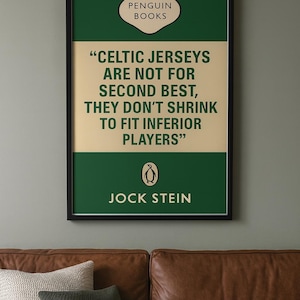 May include: Framed print featuring a quote about Celtic jerseys from Jock Stein, published by Penguin Books. The design has a green and beige color scheme with the Penguin logo. The print is displayed above a brown leather sofa with decorative pillows.