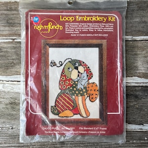 May include: A vintage "Loop Embroidery Kit" featuring a colorful dog design. The kit includes the original design printed on natural fabric, embroidery floss, and instructions. The frame size is 5"x7". The brand is "rush n' punch".