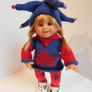 以下が含まれることがあります： ベルの付いた青いニット帽、星柄の赤と青のセーター、黒い足跡の付いた赤いズボン、白い靴を履いた人形です。