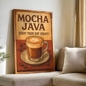 Puede incluir: Un estampado enmarcado de estilo vintage que anuncia café moca java. La obra de arte muestra una taza de café sobre un platillo, rodeada de granos de café, con el texto "MOCHA JAVA START YOUR DAY RIGHT!" en letras marrones sobre un fondo beige.