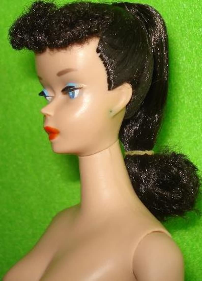 May include: A vintage doll with a fair complexion, blue eye shadow, and bright red lipstick. The doll has black hair styled in a high ponytail and a curled fringe. The doll is a classic toy.