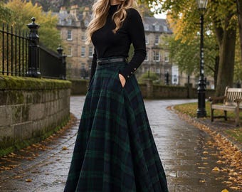May include: A long, floor-length skirt featuring a dark green and navy blue plaid pattern with a high waist, a thin black belt, and side pockets, paired with a long-sleeved black mock neck top with small gold buttons on the sleeve cuffs.