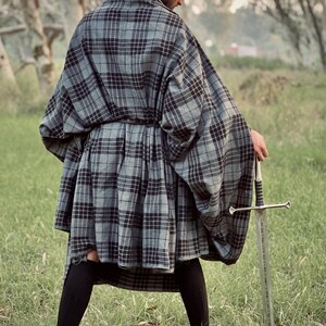 Peut inclure: Une personne portant une cape et un kilt &agrave; carreaux gris et noirs, avec un b&eacute;ret noir. La personne tient une &eacute;p&eacute;e argent&eacute;e dans un champ herbeux. La cape et le kilt sont en tissu &agrave; carreaux.
