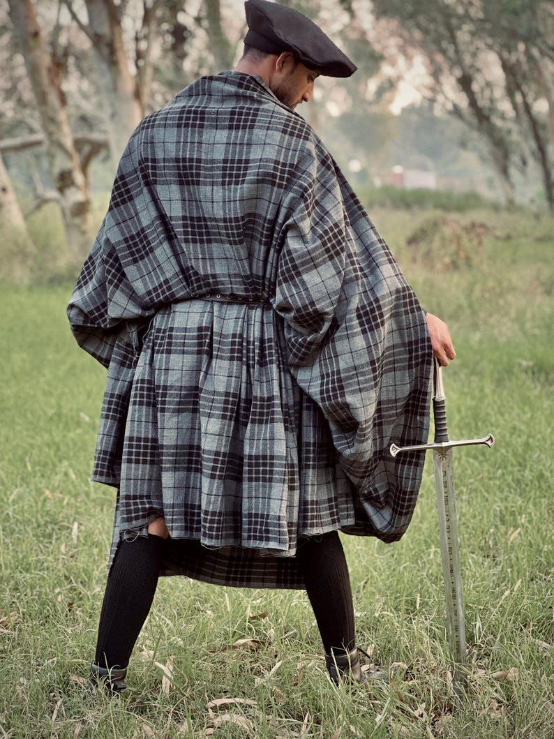 Peut inclure: Une personne portant une cape et un kilt &agrave; carreaux gris et noirs, avec un b&eacute;ret noir. La personne tient une &eacute;p&eacute;e argent&eacute;e dans un champ herbeux. La cape et le kilt sont en tissu &agrave; carreaux.