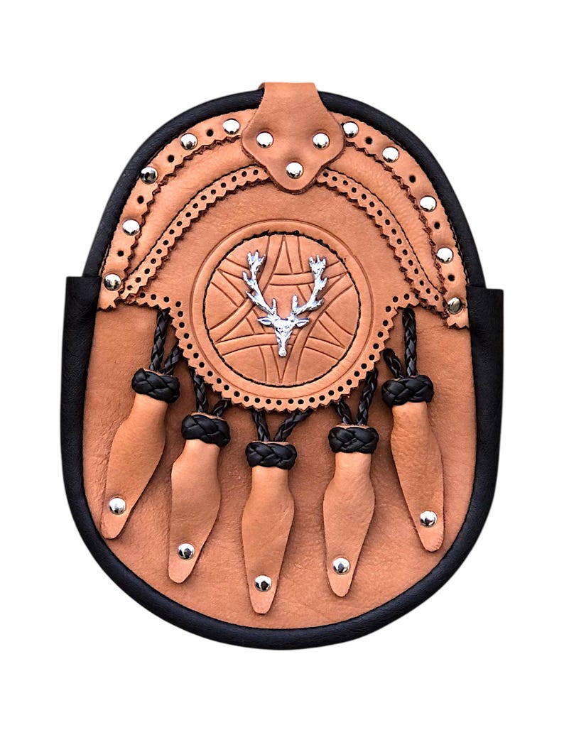 May include: A tan leather sporran with a black border and decorative silver rivets. The sporran features a central embossed design with a silver stag emblem and five tan leather tassels with silver studs.