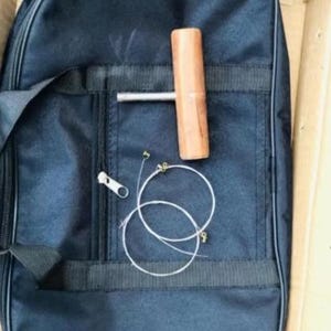May include: A black nylon guitar case with a zipper, a wooden tuning tool, and two guitar strings. The case has a pocket with a zipper. The tuning tool is brown and cylindrical.