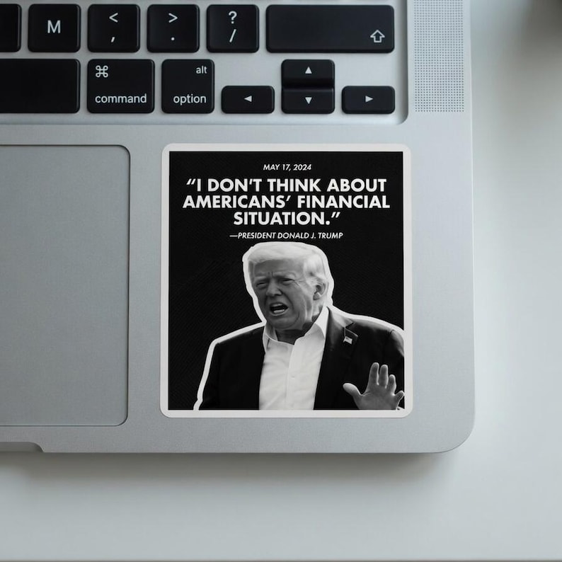 May include: A white sticker on a laptop featuring a black and white image of Donald Trump with a quote: "I DON'T THINK ABOUT AMERICANS' FINANCIAL SITUATION." The text includes the date May 17, 2024.