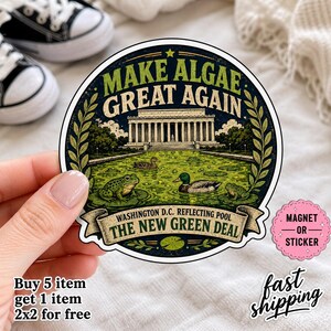 May include: A circular sticker featuring the Lincoln Memorial above a green algae-filled reflecting pool with frogs and a mallard duck. The text reads MAKE ALGAE GREAT AGAIN and WASHINGTON D.C. REFLECTING POOL THE NEW GREEN DEAL in a dark frame.