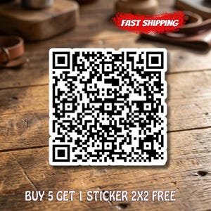 May include: A square sticker with a QR code in black and white. The sticker is on a wooden surface. The text "BUY 5 GET 1 STICKER 2X2 FREE" is at the bottom. A red banner with "FAST SHIPPING" is at the top.