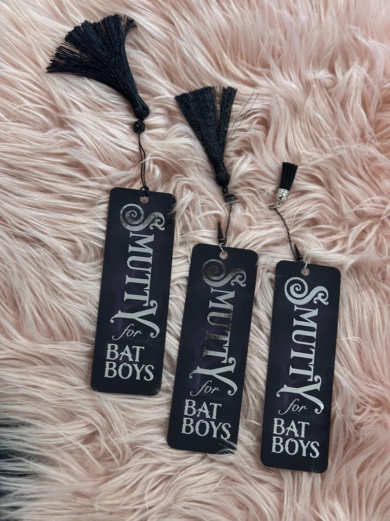 May include: Three black bookmarks with silver tassels. Each bookmark has the text "& Smutty for Bat Boys" printed in white.