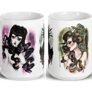 May include: Two white ceramic mugs with a black and white illustration of a woman with snakes on one mug and a green and white illustration of a woman with snakes on the other mug.