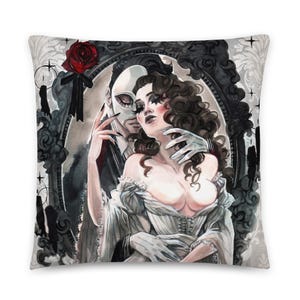 May include: A black and white illustration of a masked man and a woman embracing in a decorative frame. The man is wearing a white mask and a black suit. The woman is wearing a white dress. The background is a dark gray with a red rose.
