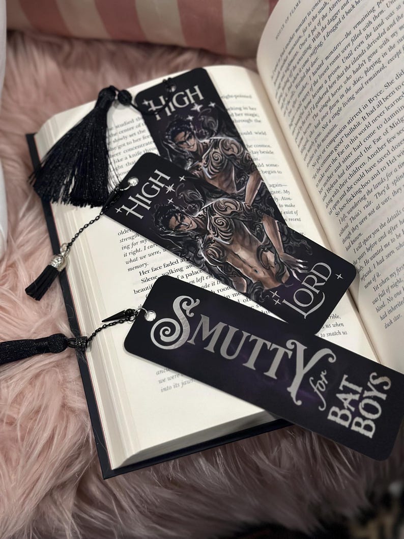 May include: Three black bookmarks with silver lettering. The bookmarks feature a dark fantasy illustration of a man with wings and a crown, the words "High Lord" and "Smutty for Bat Boys".