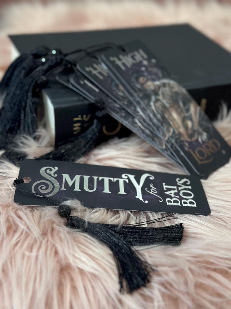 May include: Four black bookmarks with silver lettering and tassels. The bookmarks have the text "Hi Ho!" and "Smutty for Bat Boys".