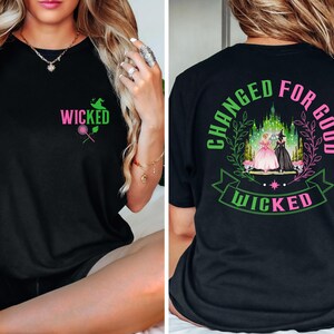 May include: Black t-shirt with the word "WICKED" in pink and green, along with a witch hat and a rose graphic. The back of the shirt features the text "CHANGED FOR GOOD" and "WICKED" with a castle and two figures.