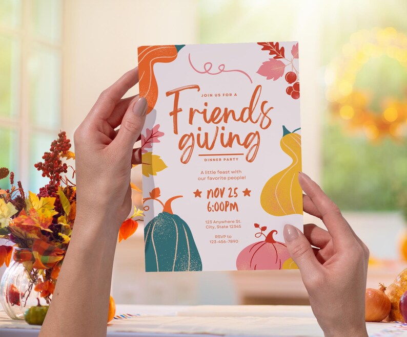 May include: A Friendsgiving dinner party invitation held by a person. The invitation features colorful illustrations of pumpkins and fall foliage. The text reads "Join us for a Friendsgiving Dinner Party" with the date and time of the event.