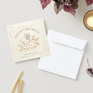 May include: A square invitation with the text "GOLDEN BIRTHDAY" and a cake illustration, accompanied by a white envelope and a gold pen. A lit candle in a gold holder and a small leaf are also present.