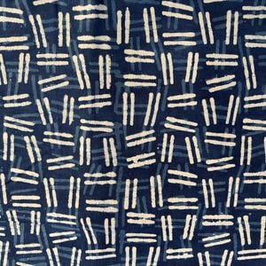 May include: Close-up of a fabric featuring a repeating pattern of white and light blue horizontal and vertical lines on a dark blue background. The design creates a woven or grid-like appearance, suitable for textiles.