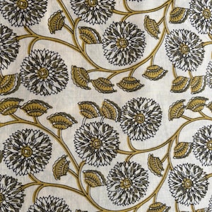May include: A close-up of a white fabric with a repeating floral pattern. The design features large, stylized flowers in shades of grey and white, with olive green leaves and stems. The overall aesthetic is reminiscent of a botanical print.