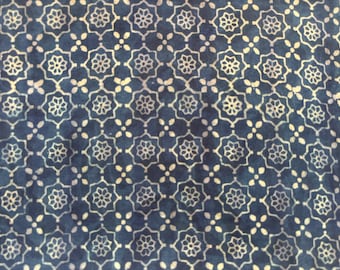 Pode incluir: Close-up de um tecido com um padrão repetitivo de motivos florais e de pontos brancos sobre um fundo azul escuro. O design cria uma disposição geométrica simétrica, adequada para têxteis ou aplicações decorativas.