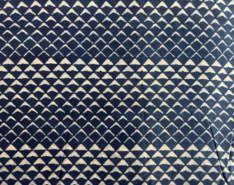 May include: Close-up of a fabric with a repeating pattern of white arrow-shaped designs on a navy blue background. The pattern creates a textured, geometric appearance, suitable for textiles or decorative items.