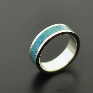 May include: A silver ring with a turquoise inlay.