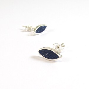 May include: A pair of silver earrings with a dark blue oval-shaped stone set in each earring.