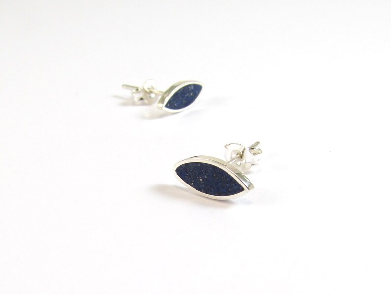 May include: A pair of silver earrings with a dark blue oval-shaped stone set in each earring.
