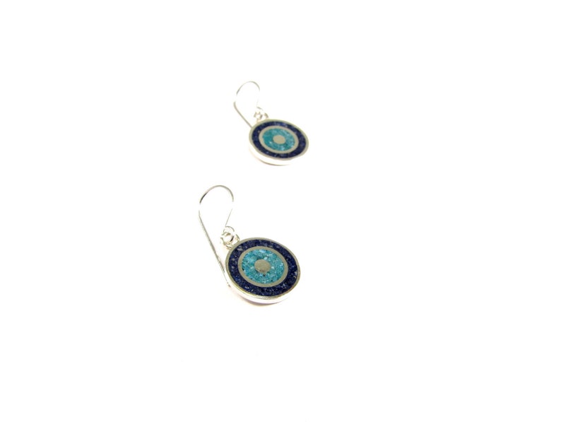 May include: A pair of silver earrings with blue and turquoise stone inlays, shaped like an eye. The earrings have a simple hook design.