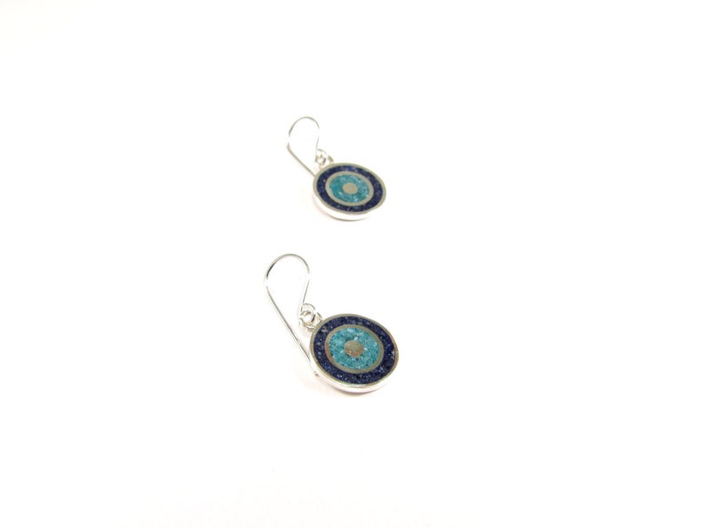May include: A pair of silver earrings with blue and turquoise stone inlays. The earrings are round and have a simple design.