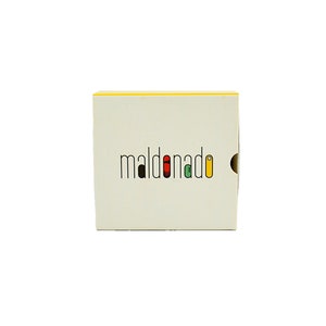 May include: A white box with a yellow top and the word "maldonado" in black letters with colored accents.