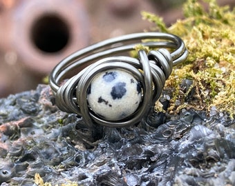 May include: A silver wire wrapped ring with a black and white dalmatian jasper stone.