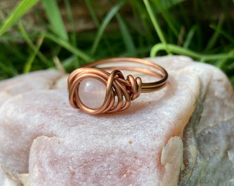 Bague en cristal de quartz rose dans des bijoux enveloppés de fil de cuivre antique