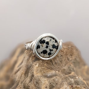 May include: A silver wire wrapped ring with a round dalmatian jasper stone.
