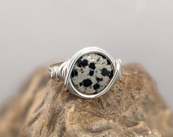 May include: A silver wire wrapped ring with a round dalmatian jasper stone.