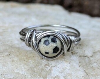 May include: A silver wire wrapped ring with a black and white dalmatian jasper stone.