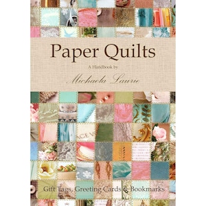 May include: A book cover with a patchwork design in shades of pink, blue, and brown. The title is "Paper Quilts: A Handbook by Michaela Laurie". The subtitle is "Gift Tags, Greeting Cards & Bookmarks".